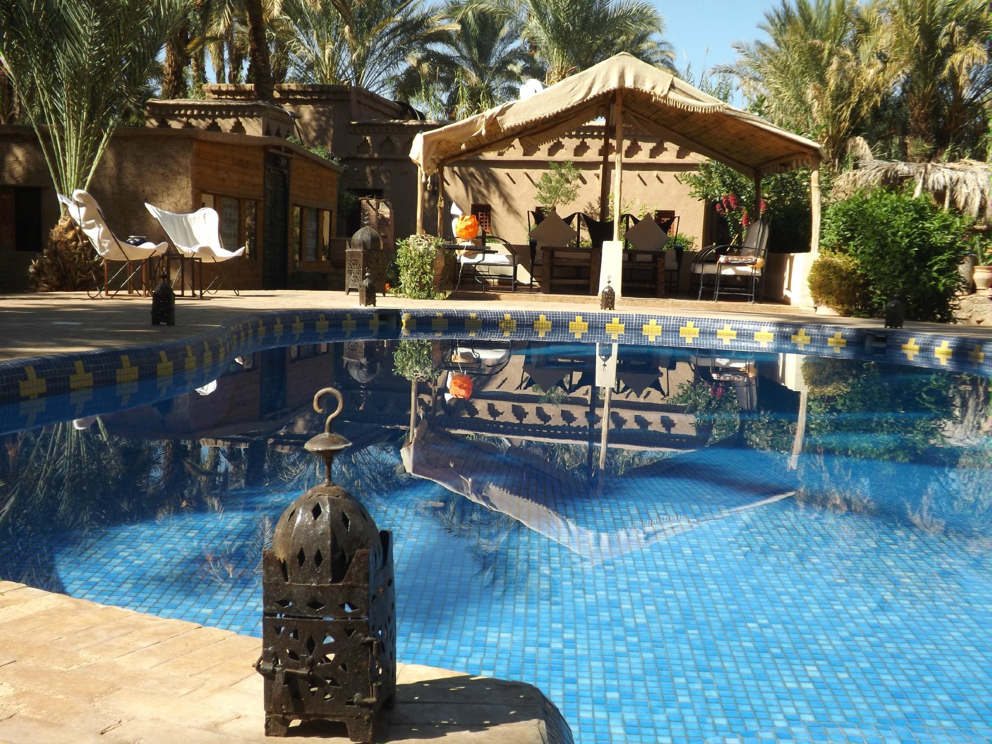 La piscine de Bab El Oued entourée de palmiers et de lodges en terre